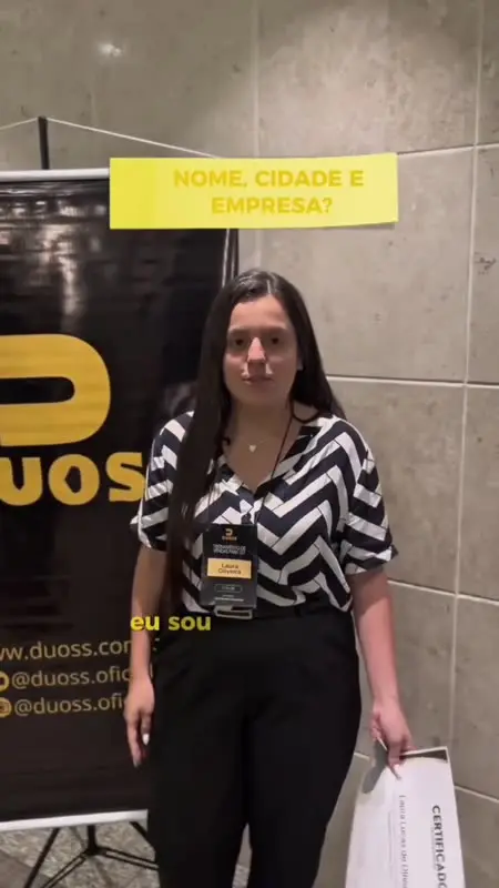 Participante do 1º Treinamento de Vendas para SST gravando depoimento ao lado do banner da DUOSS.